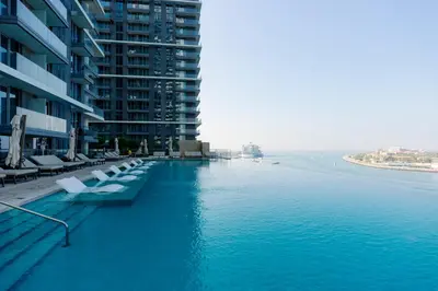 a swimming pool next to a large building next to the water at Luxurious Waterfront 1BR with Stunning Sea Views - 15AB02 in Dubai