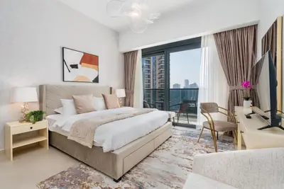 a bedroom with a large bed and a desk with a computer at Mystic - Act One Tower in Dubai