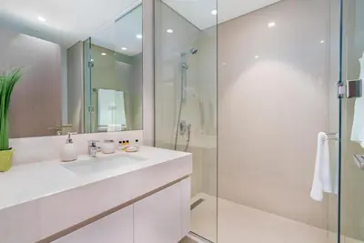 a white bathroom with a sink and a shower at Mystic - Act One Tower in Dubai