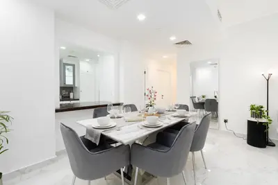 a white dining room with a table and chairs at Mystic - Fully Renovated Spacious 2BR Apt. with Burj Views in Dubai