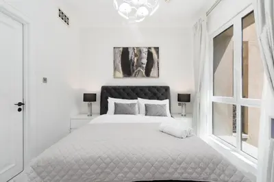 a white bedroom with a large bed and a window at Mystic - Fully Renovated Spacious 2BR Apt. with Burj Views in Dubai