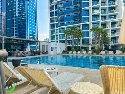 a swimming pool with chairs and some tall buildings at Mystic - Damac Maison Prive Tower B in Dubai