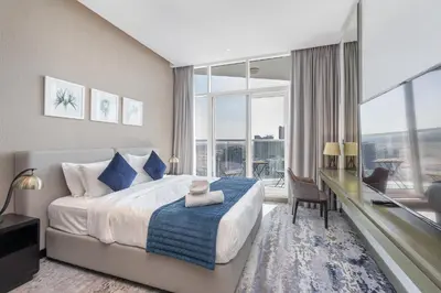 a bedroom with a bed and a desk with a large window at Mystic - Damac Maison Prive Tower B in Dubai