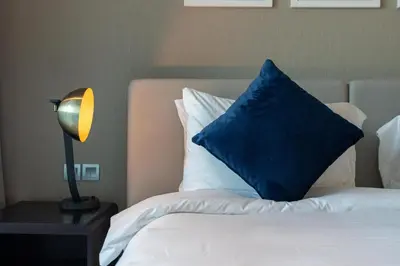 a bed with a blue pillow and a lamp on a table at Mystic - Damac Maison Prive Tower A in Dubai