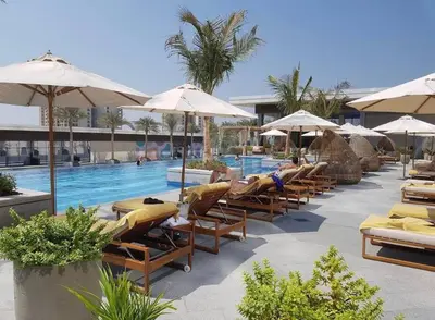 a swimming pool with lounge chairs and umbrellas at Luxury Studio in High Floor Full Sea View in The Palm Tower Plam Jumeirah in Dubai
