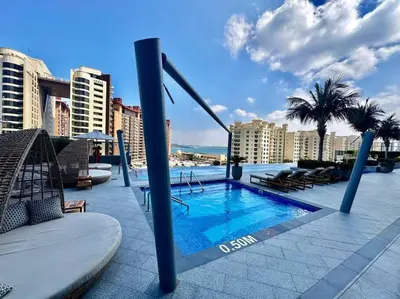 a swimming pool on a building with palm trees and buildings at Luxury Studio in High Floor Full Sea View in The Palm Tower Plam Jumeirah in Dubai