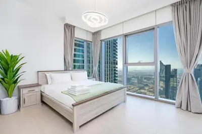 a white bedroom with a bed and large windows at Burj Khalifa & Dubai Dancing Fountain View, 54th Floor & Dubai Mall Access in Dubai