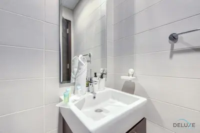a white bathroom with a sink and a mirror at Tranquil 3BR Townhouse at Albizia Damac Hills 2 by Deluxe Holiday Homes in Dubai