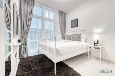 a white bedroom with a bed and a large window at Tranquil 3BR Townhouse at Albizia Damac Hills 2 by Deluxe Holiday Homes in Dubai