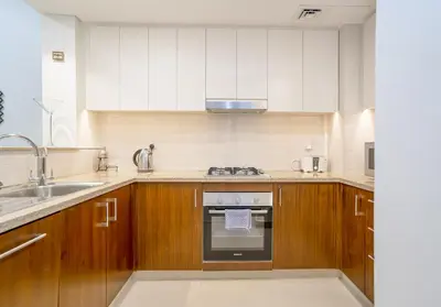 a kitchen with wooden cabinets and a stove top oven at Vacay Lettings - Stunning Burj Khalifa fountain view near Dubai mall in Dubai