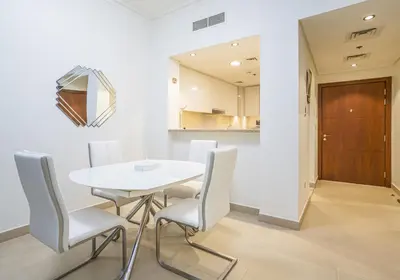 a white dining room with a white table and chairs at Vacay Lettings - Stunning Burj Khalifa fountain view near Dubai mall in Dubai
