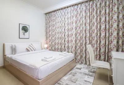 a small bedroom with a bed and a chair at Vacay Lettings - Stunning Burj Khalifa fountain view near Dubai mall in Dubai
