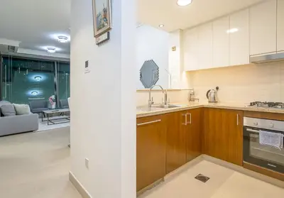 a kitchen with wooden cabinets and a living room at Vacay Lettings - Stunning Burj Khalifa fountain view near Dubai mall in Dubai