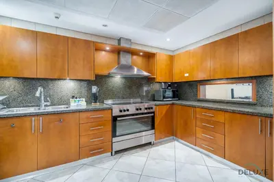 a kitchen with wooden cabinets and a stove top oven at Sophisticated 3BR w/ Assistant’s Room at Al Fattan Marine Towers 2 JBR by Deluxe Holiday Homes in Dubai