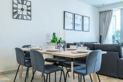 a dining room table with chairs and a clock on the wall at Sophisticated 3BR w/ Assistant’s Room at Al Fattan Marine Towers 2 JBR by Deluxe Holiday Homes in Dubai