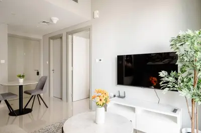 a white living room with a tv on a wall at Pool View One Bed Room Business Bay in Dubai