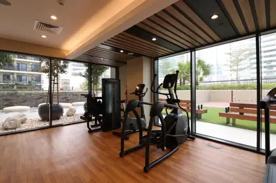 a gym with treadmills and ellipticals in a room with windows at Pool View One Bed Room Business Bay in Dubai