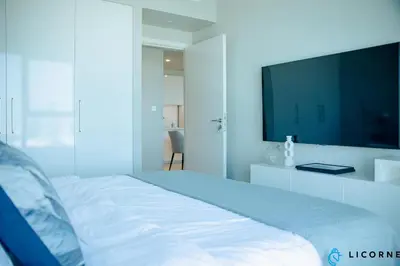 a bedroom with a white bed with a tv on the wall at Unveil Downtown Luxury, 1BR Majestic Skyline Views - Downtown Views ll in Dubai