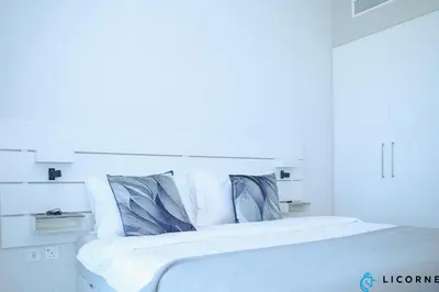 a white bed with white sheets and blue pillows at Unveil Downtown Luxury, 1BR Majestic Skyline Views - Downtown Views ll in Dubai