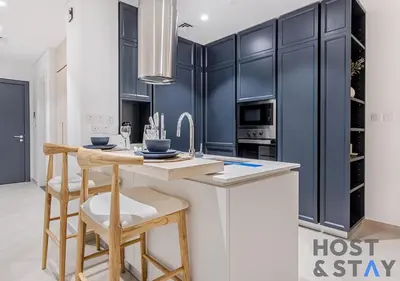 a kitchen with black cabinets and a counter with stools at Luxury Studio at Wilton Park - MBR in Dubai