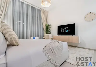 a white bedroom with a bed and a tv at Luxury Studio at Wilton Park - MBR in Dubai