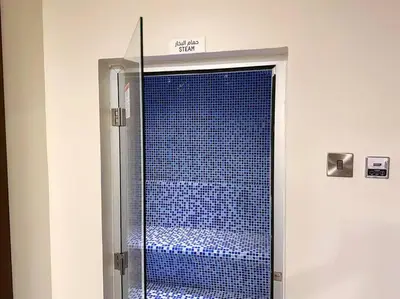 a glass shower door with blue tile in a bathroom at TruStay Vacation Home Rentals - Business Bay in Dubai