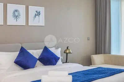 a bedroom with two beds with blue and white pillows at Stunning 1 BR Damac Maison Prive in Dubai
