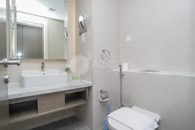 a bathroom with a sink and a toilet and a mirror at Stunning 1 BR Damac Maison Prive in Dubai