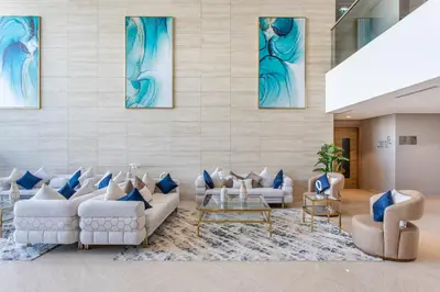 a lobby with white furniture and blue paintings on the wall at Holiday Studio In JVC 0107, Dubai in Dubai