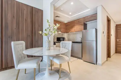 a dining room with a table and chairs and a refrigerator at Holiday Studio In JVC 0107, Dubai in Dubai