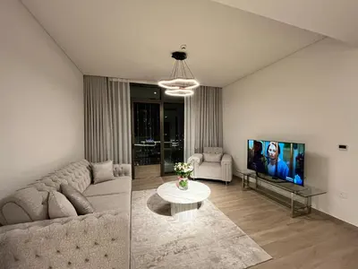 a living room with a couch and a tv at Palace Dubai Creek Harbour Residences Skyline Apartment in Dubai