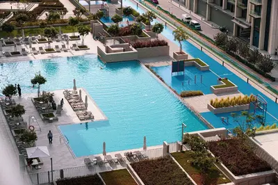 an overhead view of a large swimming pool in a building at Burj Khalifa View, 2 Balcony w Lounge, Dubai Mall Access, Gym, Infinity-Pool, Playground, BBQ, Family Friendly in Dubai