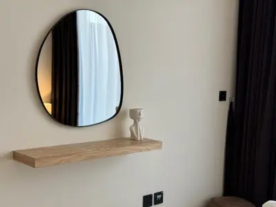 a mirror on a wall with a vase on a shelf at ASHRI HH, Luxurious Apt in JVC in Dubai