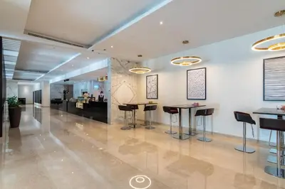 a lobby with stools and tables in a building at The Smart Concierge - Damac Maison Prive in Dubai