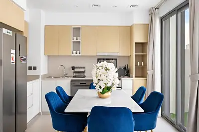 a kitchen with blue chairs and a table with a vase of flowers at Luxurious 6-Sleeper Villa with Large Outdoor Patio in Dubai