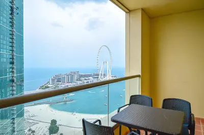 a balcony with a table and chairs and a view of the ocean at Luxury Escapes - Amazing Sea View - 4 Bedrooms Apt with Maids room in JBR in Dubai