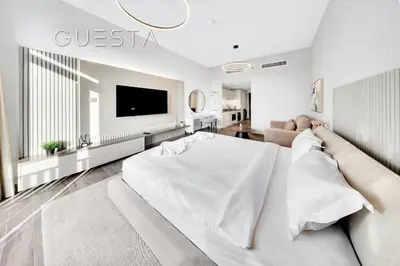 a white living room with a bed and a couch at Belgravia Square, Jumeirah Village Circle in Dubai