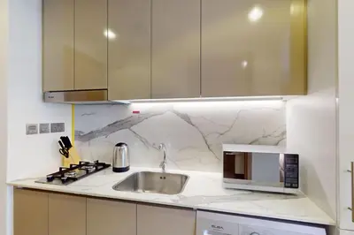 a white kitchen with a sink and a microwave at Azizi Riviera 16 - Charming Studio in Dubai
