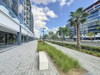 a bench on a sidewalk next to a street with buildings at Azizi Riviera 16 - Charming Studio in Dubai