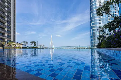 a swimming pool with blue tiles in the middle of two tall buildings at 5242 Tower 2 - Chic Two Bedroom in Dubai