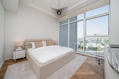 a white bedroom with a bed and a large window at Upgraded Banyan Tree 2 Bed in JLT in Dubai