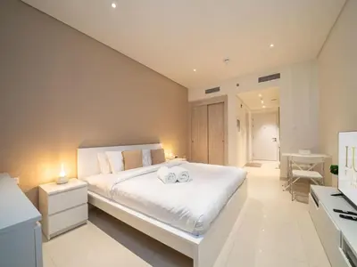 a bedroom with a large white bed with two towels at Seven Palm Studio with Rooftop Infinity Pool in Dubai