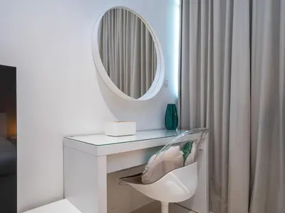 a white dressing table with a mirror and a chair at Seven Palm Studio with Rooftop Infinity Pool in Dubai