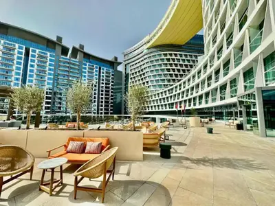 a large building with tables and chairs and buildings at Seven Palm Studio with Rooftop Infinity Pool in Dubai