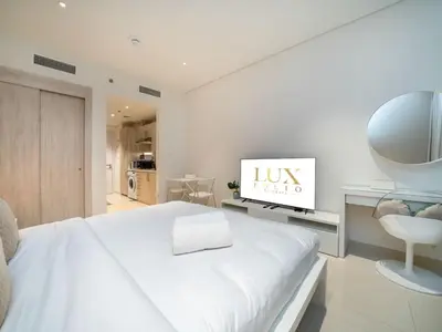 a white bedroom with a large bed and a chair at Seven Palm Studio with Rooftop Infinity Pool in Dubai