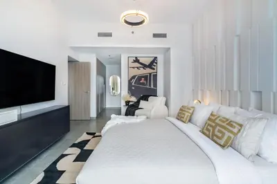 a white bedroom with a large bed and a flat screen tv at The Smart Concierge - Stella Maris in Dubai