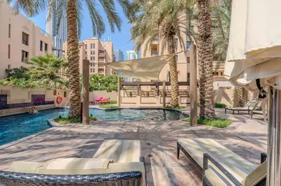 a swimming pool with palm trees in a courtyard at GuestReady - Groove Getaway in Downtown Dubai in Dubai