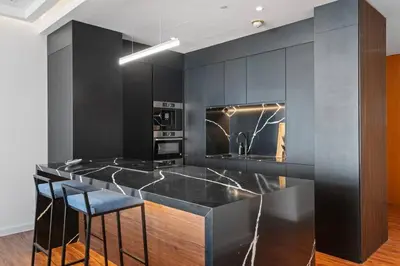 a kitchen with black cabinets and a counter with bar stools at Burj Khalifa & Downtown Views - 3BR Family Retreat Near Dubai Mall in Dubai
