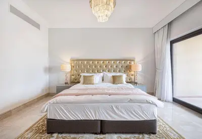 a white bedroom with a large bed and a chandelier at Fairmont North 2BR 2 Balconies Sea View in Dubai