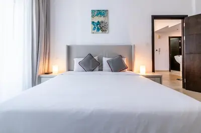 a bedroom with a large white bed and a bathroom at 1BD apartment in Torch Tower, Dubai Marina in Dubai